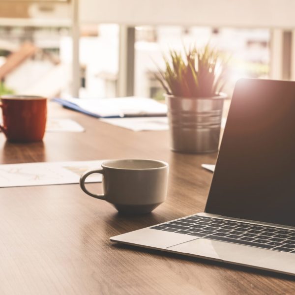 Laptop computer with opened lid on table in meeting room of office workspace.